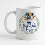 White ceramic mug featuring a balloon bouquet and the French greeting 'Bonne Fête Papa' in script, surrounded by a laurel wreath.